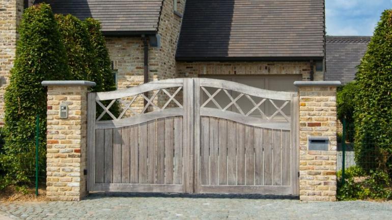 A classic wooden swing driveway gate with an arch and crosses at the top