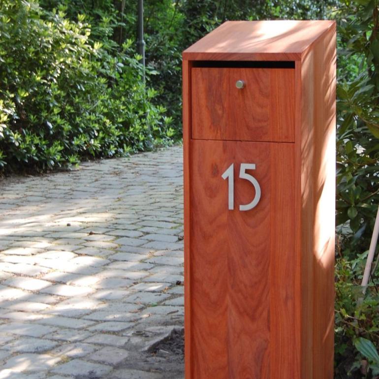 Een vrijstaande houten brievenbus met een huisnummer