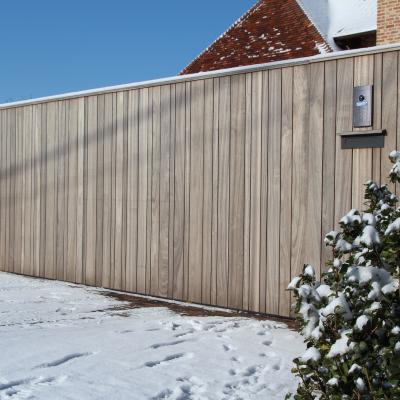 A wooden sliding gate for a driveway with an integrated intercom system and a mailbox