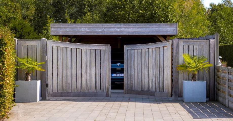 Een houten draaipoort met verticale planken als toegang tot een garage