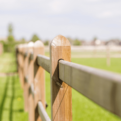 A wooden fence with rails and boards sliding through square posts