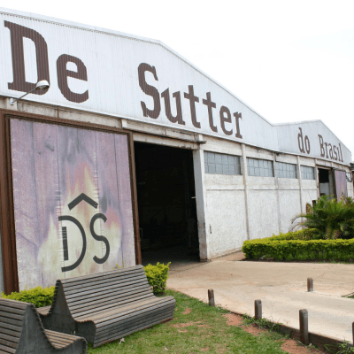 Wooden benches outside of De Sutter Naturally warehouse in Brazil with some green areas.