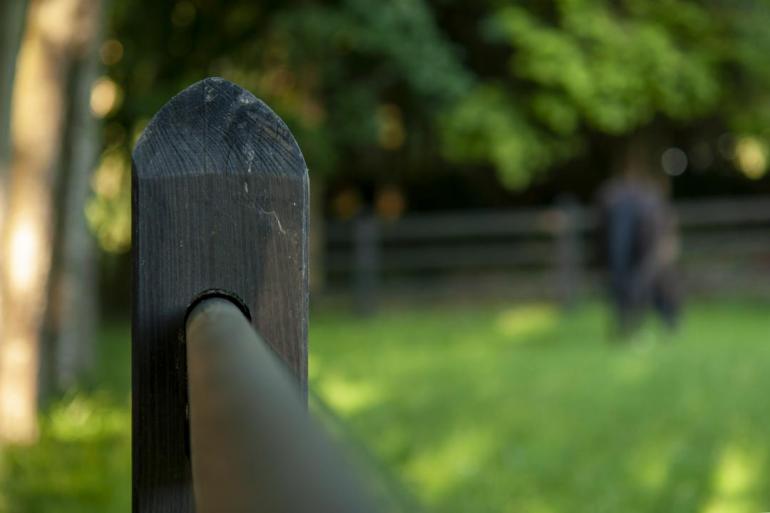 Close-up van de zwarte houten vierkante paal van een zwart houten hek