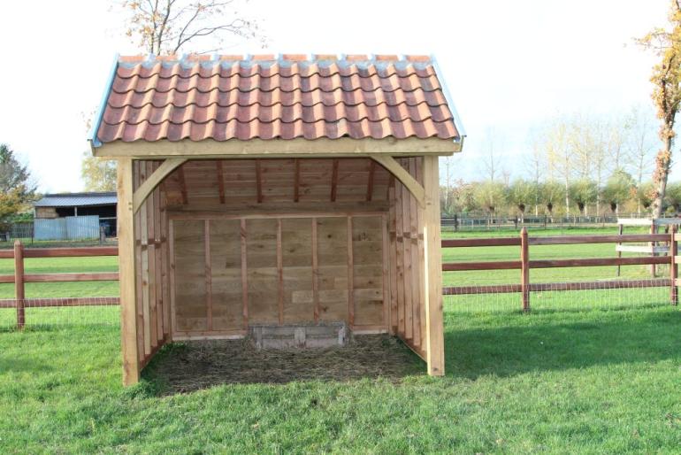 Een houten schuilstal met dakpannen voor kleine buitendieren