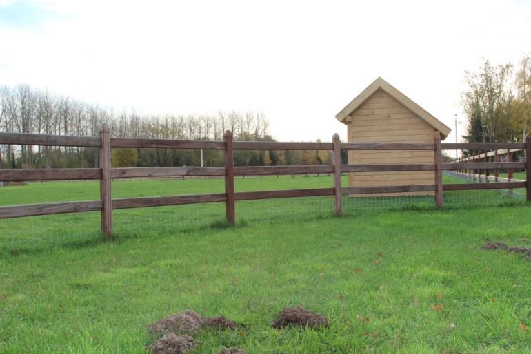 A wooden shelter for small outdoor animals with wooden fences around it