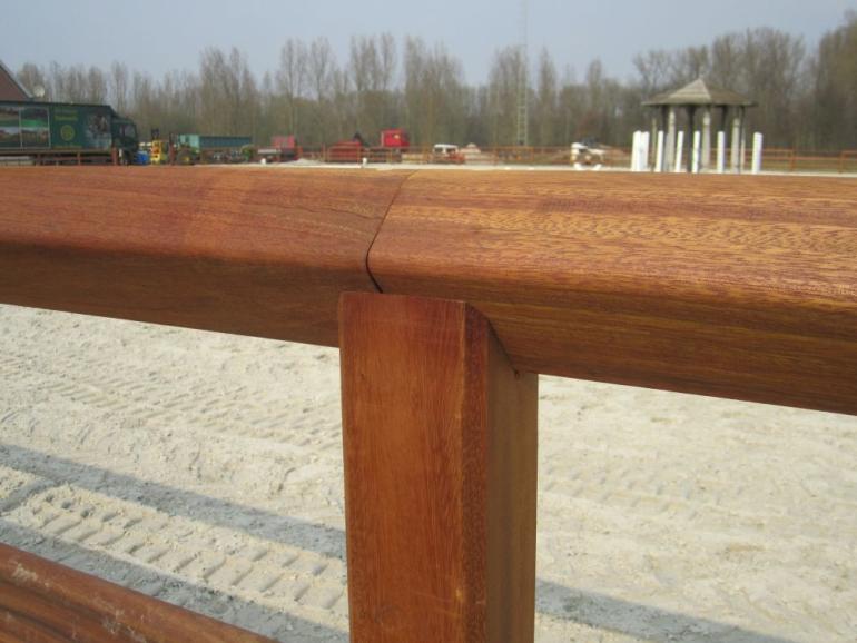 Een doorlopende bovenste rail van een houten paddock-omheining bovenop de paal