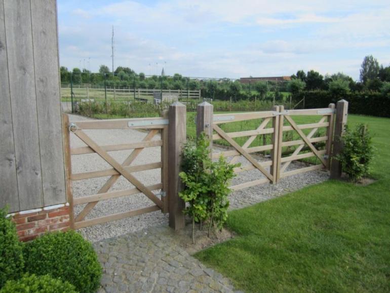 Een dubbele houten poort naast een houten tuindeur