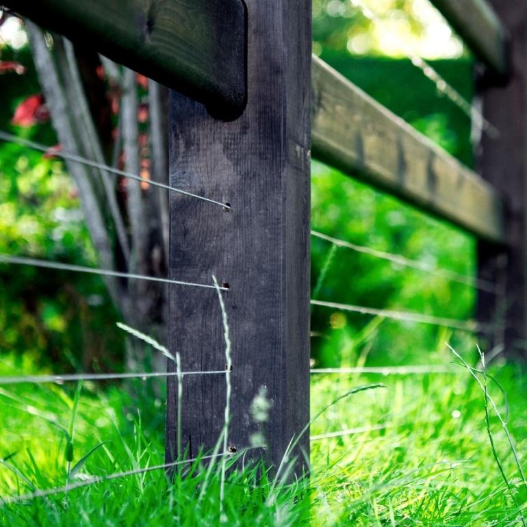 Une clôture en bois avec des rails et des fils pour le bétail