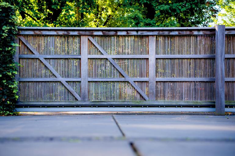 L'arrière d'un portail coulissant en bois avec des planches verticales où l'on peut voir à travers