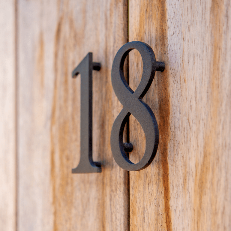 Een close-up van een huisnummer op een houten vlak