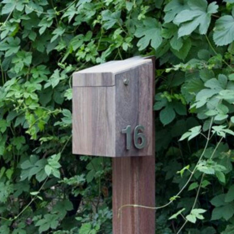 Een houten brievenbus met een huisnummer erop