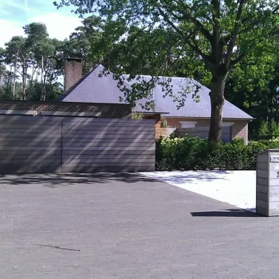 Een houten oprit draaipoort met horizontale planken en een modern ontwerp. Een moderne houten brievenbus met het huisnummer