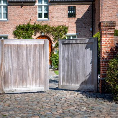 A wooden swing driveway gate with vertical boards next to eachother and modern design