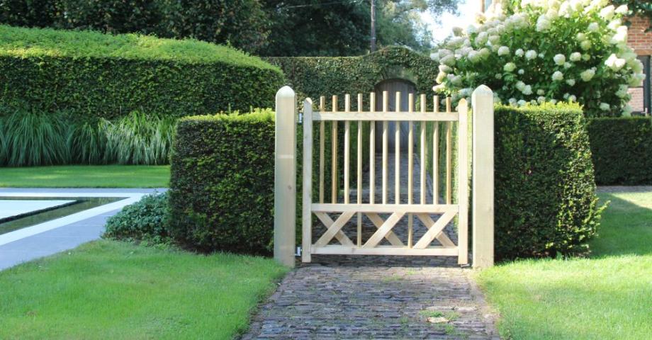 A wooden gate with small vertical boards in the middle of a garden.