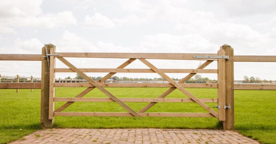 Een houten poort bevestigd aan een houten omheining met 2 rails