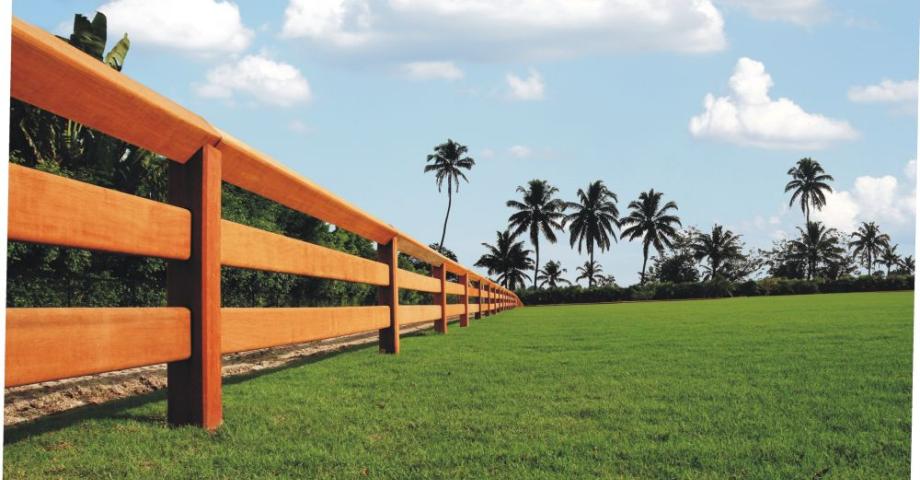 Une clôture en bois avec deux rails, des planches qui glissent à travers les poteaux et un rail supérieur continu.