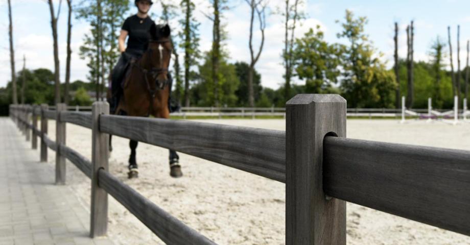 A riding arena with two-rail wooden fences where the boards slide into the square posts.