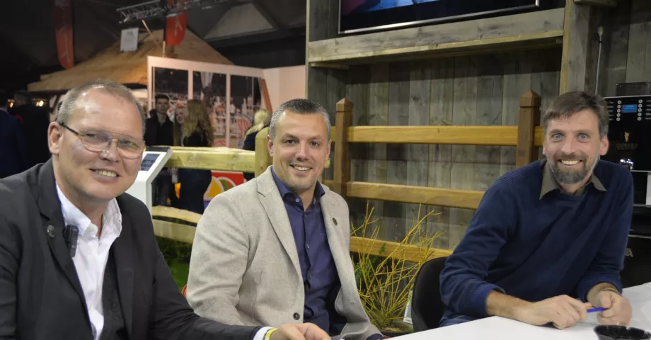 Three men in front of wooden fences with rails