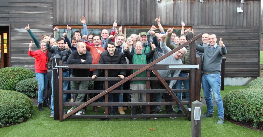 A group of haapy people in front of a wooden field gate with an arched top