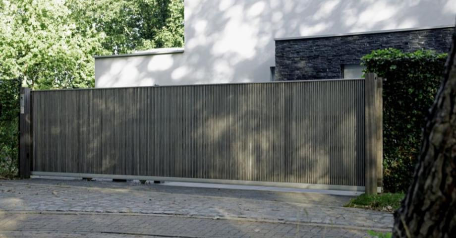 A wooden sliding driveway gate with a modern design and an intercom system