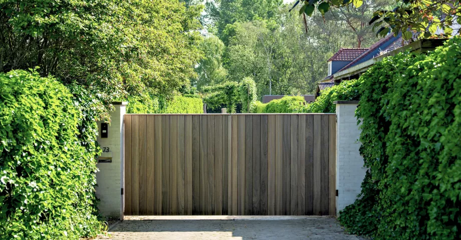 A wooden swing driveway gate with vertical boards next to eachother and modern design